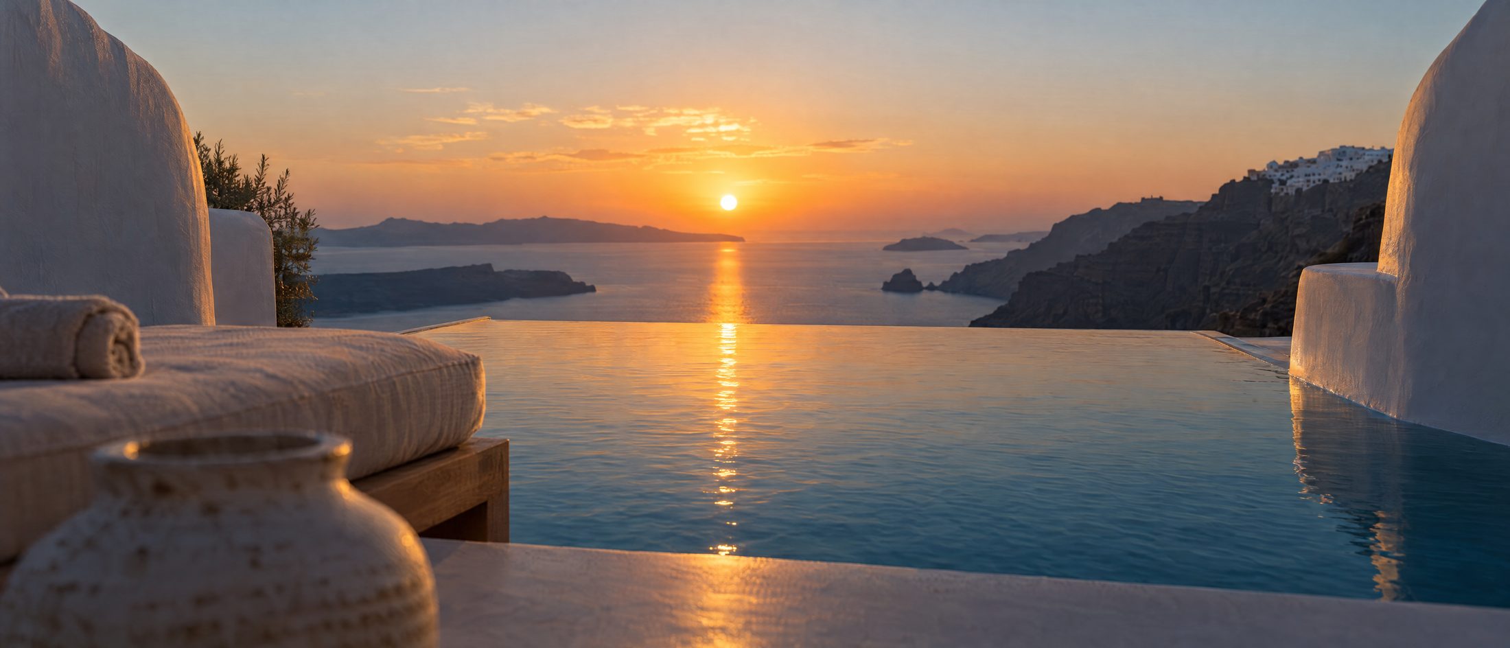 A private infinity pool on a whitewashed terrace at the edge of a caldera cliff