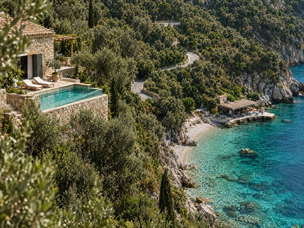 A small villa on a steep olive slope above a secluded turquoise shingle cove