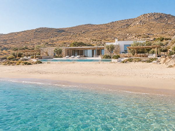 A low villa set back behind a wide open sandy beach under dry hills