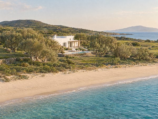 A quiet villa among low green fields behind a long empty sandy beach