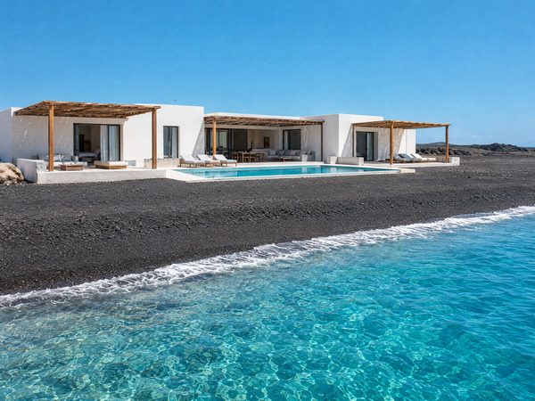 A low modern villa with a pool behind a long black volcanic sand beach
